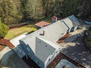 Aerial view of Large grey home surrounded by trees