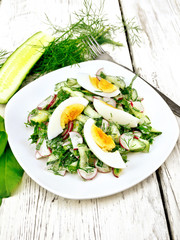 Salad with radish and egg in plate on wooden table