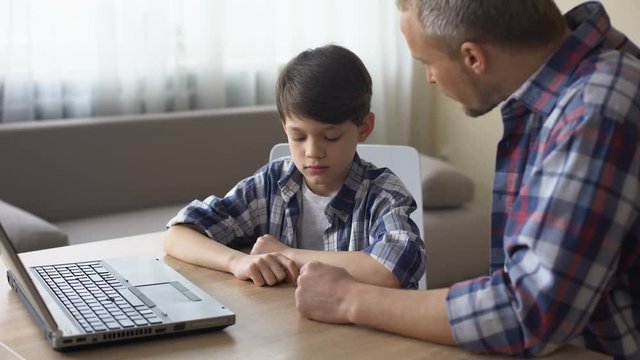 Strict father scolding his little son for computer addiction, family problem