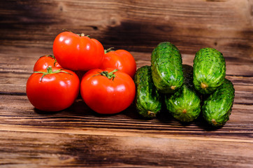 Ripe tomatoes and cucumbers on wooden table