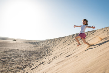 Happy child running down sand dune