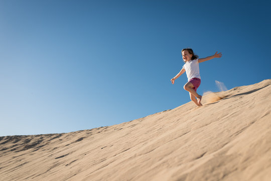Girl running down sand dune