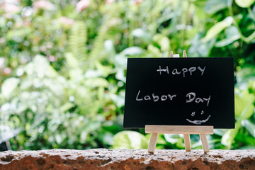 Happy labor day greeting card concept, Chalk board with text HAPPY LABOR DAY with green fresh garden background