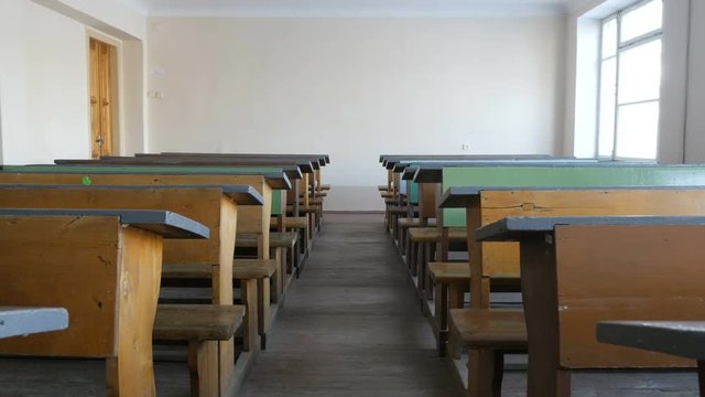 Empty classroom with wooden school desks and chairs, view from inside
