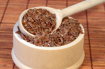 Flax seeds in wooden bowl with spoon close up