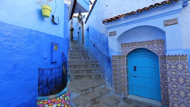 Panorama of traditional old blue street with color pots inside Medina of Chefchaouen, Morocco