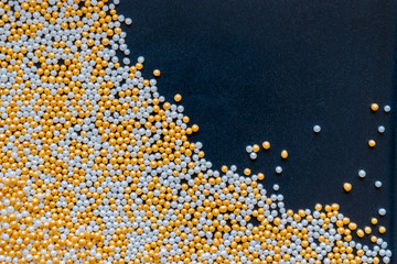 White, Gold, Shiny and Tiny Sugar Balls Background on Black Background Surface with Free Space