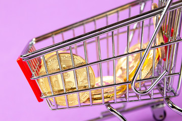Empty shopping cart on the lilas background with bitcoin