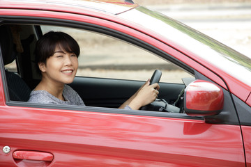 Young asian woman in casual wear driving a car and smiling. Confident and beautiful.