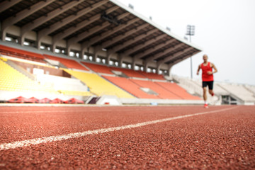 Sport Background. Runner. Athletic man running on stadium track. Selective focus.