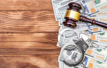 Gavel with handcuffs and money on the wooden table. Top view. Law background.
