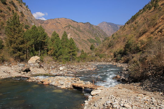 Simple timber bridge and Langtang Khola, river in Nepal. Scene near Shyaphru Besi. Langtang National Park.