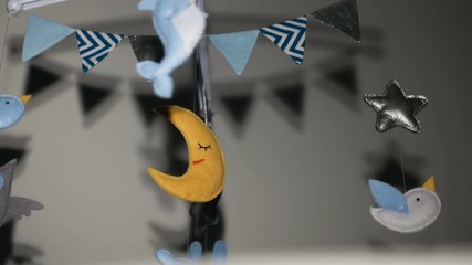 baby mobile with blue hand-stitched animal and bird toys with yellow moon on white wall background