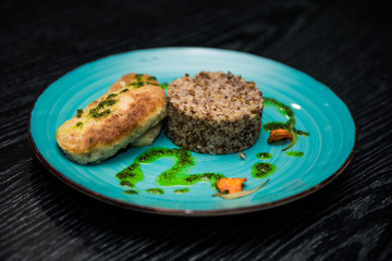 Fototapeta na wymiar buckwheat porridge with a cutlet on a blue plate. Buckwheat cereal with schnitzel.