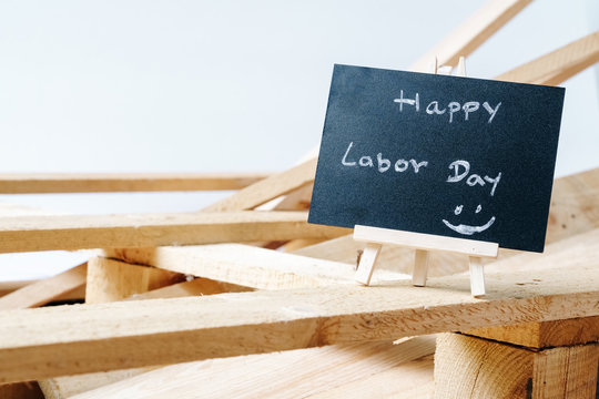 Small chalk board with text Happy Labor Day with wooden pallet background on white background. International Workers' Day