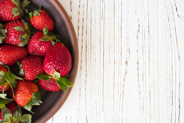 Strawberry. Fresh strawberry on white wooden background with copy space for text. Heap of Red strewberry on a plate close up.