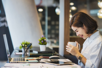 Businesswoman working on laptop while drinking coffee in the office	