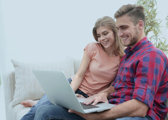 smiling young couple with laptop sitting on the couch