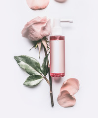 Pink Roses essential cosmetic product bottle with branding mock up and rose flowers and petals on...