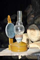Old kerosene lamp standing in old barn with firewood, retro background texture