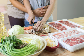 Young asian couple cutting vegetable in the kitchen