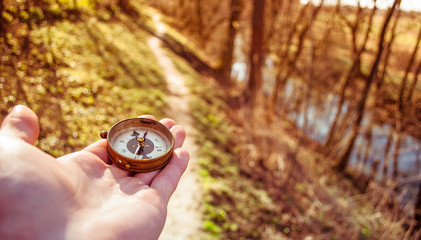 Traveler holds a compass in his hand, traveling around the world, looking for a road, close-up