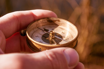 Traveler holds a compass in his hand, traveling around the world, looking for a road, close-up