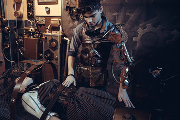 A scientist, a mechanic, includes a control lever to revive an artificial robot girl on a desk in his steampunk lab.