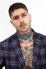 Handsome and confident tattooed man portrait wearing tartan jacket