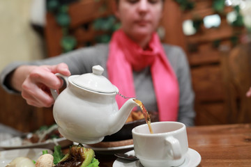 Woman filling cup of tea