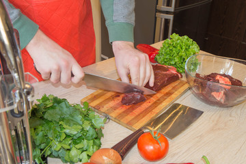 he is cutting meat or steak for a dish on wooden board