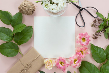 Flat lay of vintage gift box of Kraft eco paper with flower frame wreath on pink background, top view with copy space