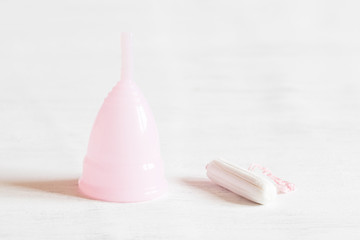 Pink fame cup and white tampon on white vintage background. Copy space, selective focus.