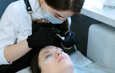Fototapeta premium Beauty treatment. Beautician's hands put a solution on curler eyelash curler. lash lamination.