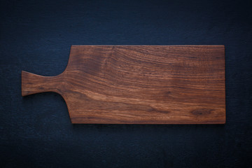 Walnut handmade wood cutting board on black wooden board