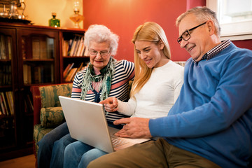 Young woman pointing on computer and showing to grandparetns images