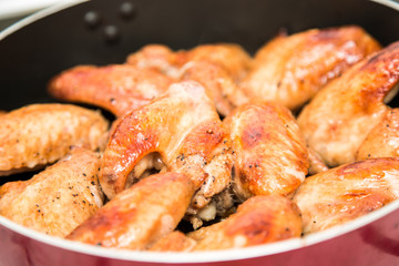 Closeup of baked chicken wings in baking pan. Selective focus