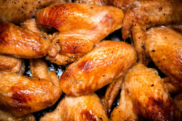 Closeup of baked chicken wings in baking pan. Selective focus