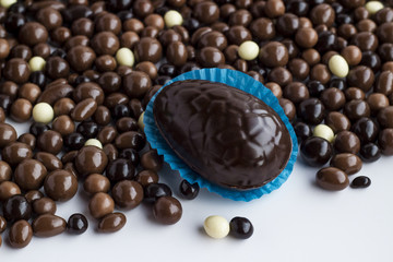 Easter Egg Shape Chocolate on blue paper with dark ball chocolates.Conceptual image of Easter Festival