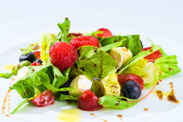 Appetizing fresh vegetarian salad with different berries, tomatoes, meat, basil leaves and sauce, close-up. For menu design