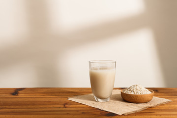 The water that clean out rice like milk in the glass, and Some rough rice in wooden bowl