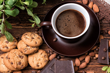 Coffee cup, beans, almond, chocolate and cookie on old kitchen table. Top view.