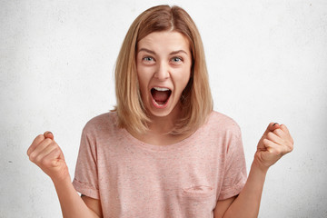 Angry irritated furious woman ready to fight, clenches fists and shouts at husband, sort out family relationships, dressed casually, isolated over white studio background. People, anger, irritation