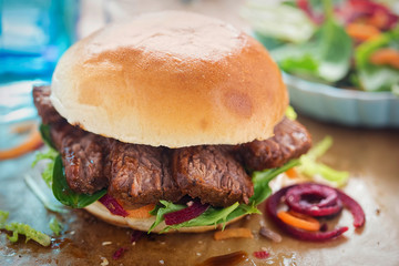 Bun with barbecue beef brisket admixed leaves salad 