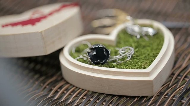 Close-up shot of the necklace on the moss in the wooden box in form of heart.