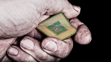 Dirty hand crushes microprocessor with critical bug. Broken computer chip in hacker's fist on black...