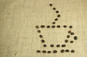 Cup of coffee made from coffee beans on rustic sack background.