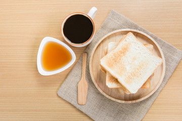 top view of toasts with honey and hot black coffee on wooden table. breakfast for modern lifestyle.