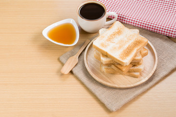 crispy toasts served with honey and hot black coffee on wooden table, copy space for text. breakfast for modern lifestyle concept.
