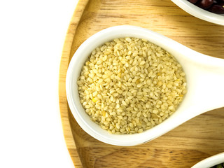 White sesame in a wooden spoon top view